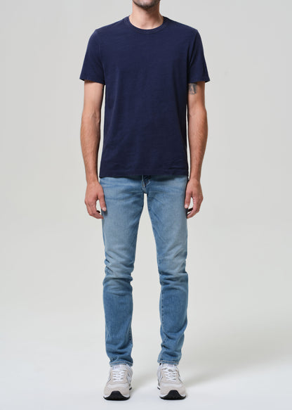 Person wearing a navy t-shirt and light blue jeans on a grey background
