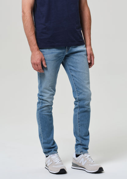 Person wearing a navy t-shirt and light blue jeans on a grey background