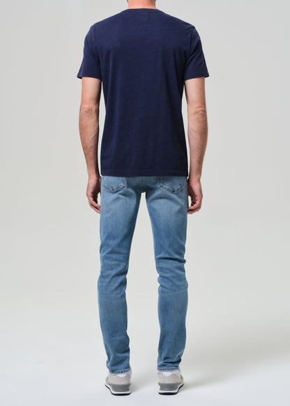 Person wearing a navy t-shirt and light blue jeans on a grey background