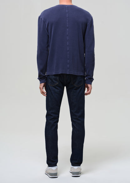 Person wearing a navy long-sleeve shirt and dark pants on a plain background