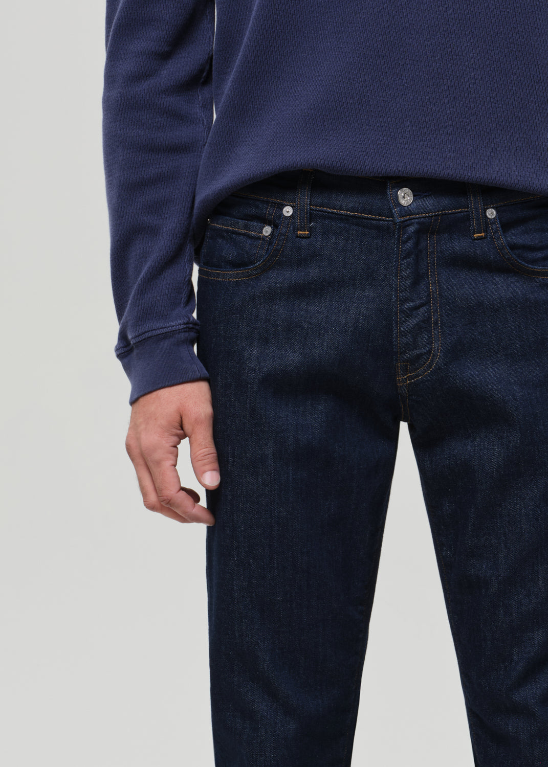 Person wearing dark blue jeans and a matching long-sleeve shirt on a light gray background