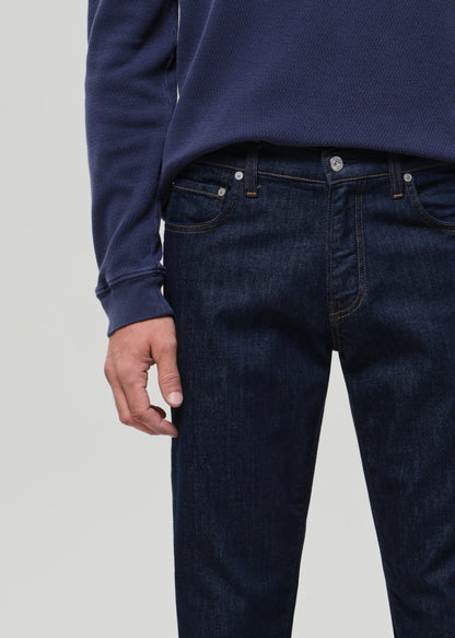 Person wearing dark blue jeans and a matching long-sleeve shirt on a light gray background