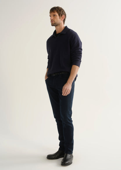 Person wearing dark navy jeans with a navy long sleeve top and black boots, front angled view.
