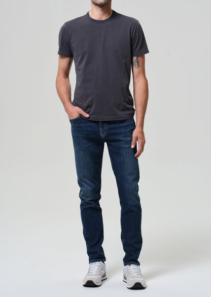 Person wearing a dark gray t-shirt and blue jeans on a white background