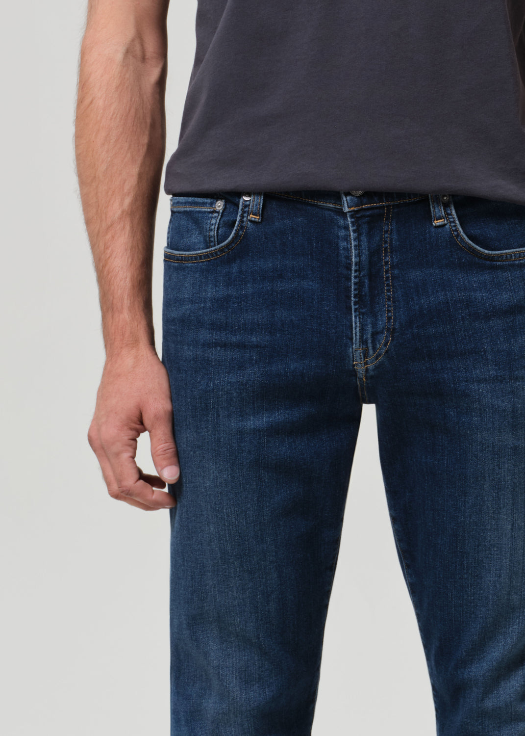 Person wearing blue jeans and a dark shirt on a light gray background