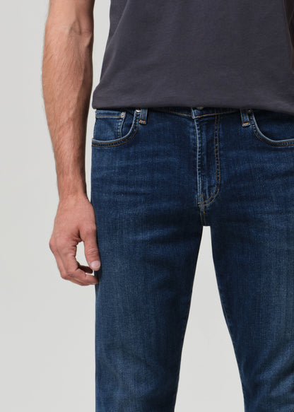 Person wearing blue jeans and a dark shirt on a light gray background