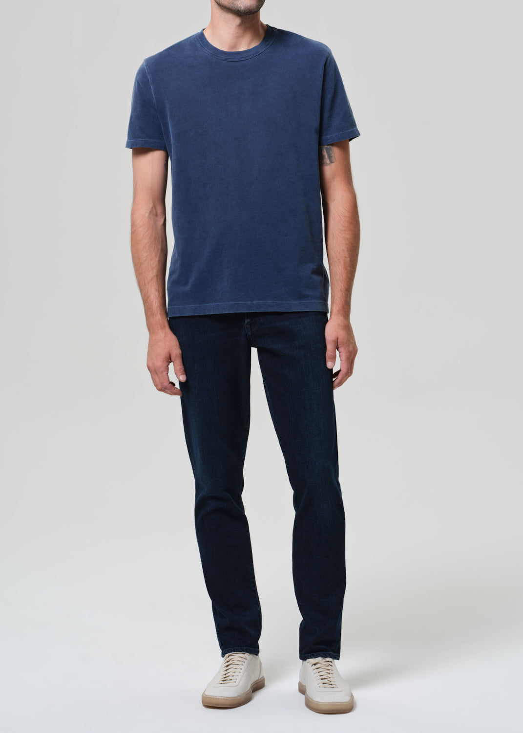 Person wearing a blue t-shirt and dark jeans