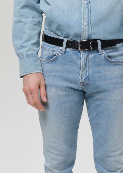 Close-up of light blue straight leg jeans on a grey background.