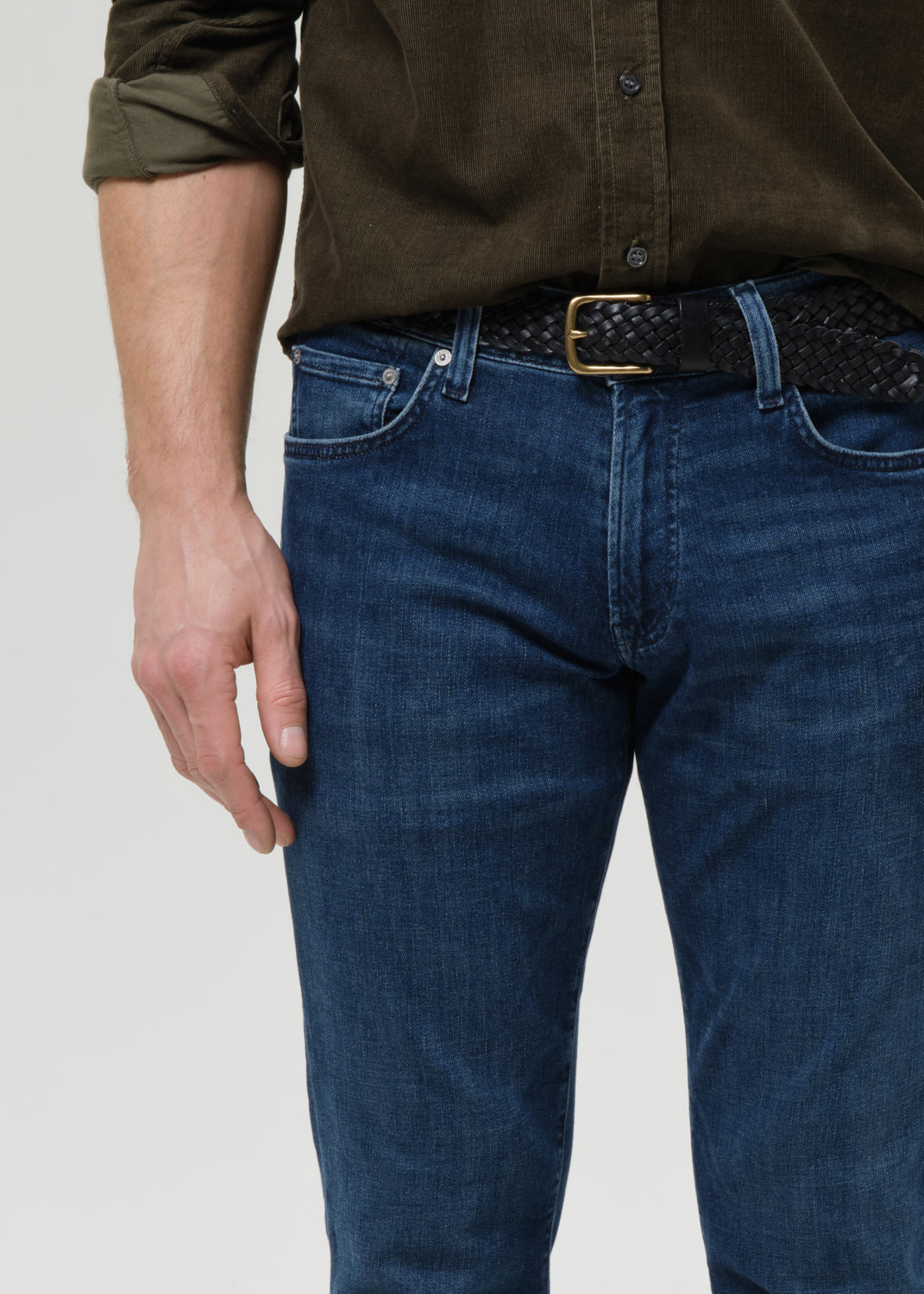 Close-up of medium blue straight leg jeans on a grey background.