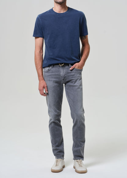 Person wearing a navy t-shirt and gray jeans on a grey background
