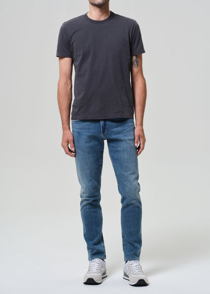 Person wearing a dark gray t-shirt and blue jeans on a plain background