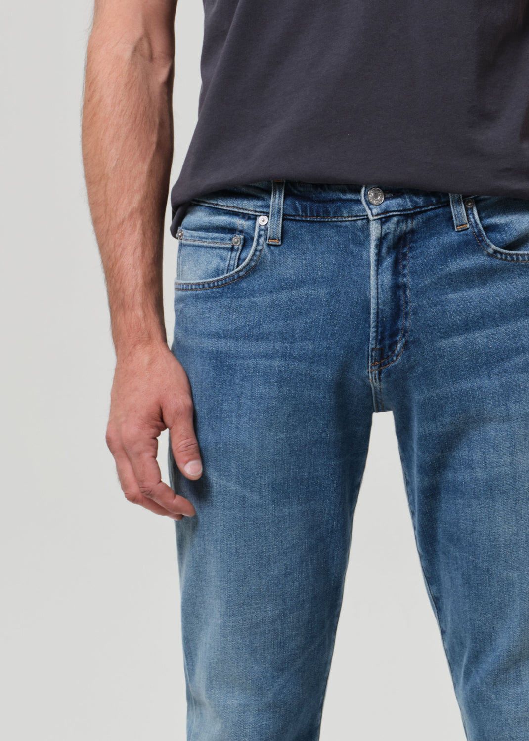 Person wearing blue jeans and a dark shirt on a light gray background