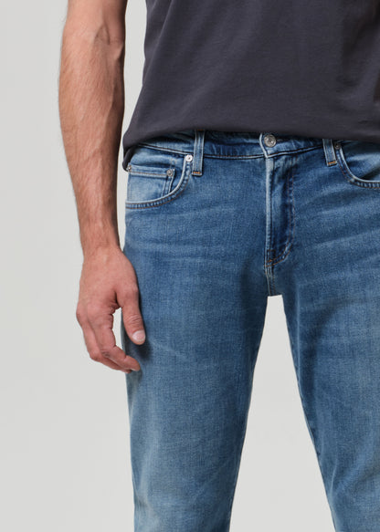 Person wearing blue jeans and a dark shirt on a light gray background