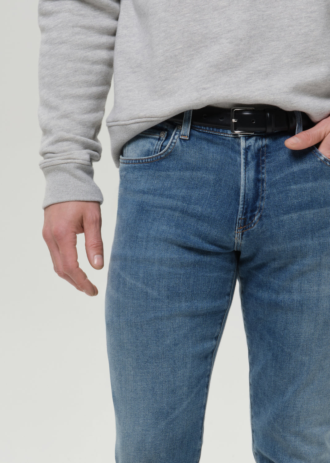 Close-up of medium blue straight leg jeans on a grey background.