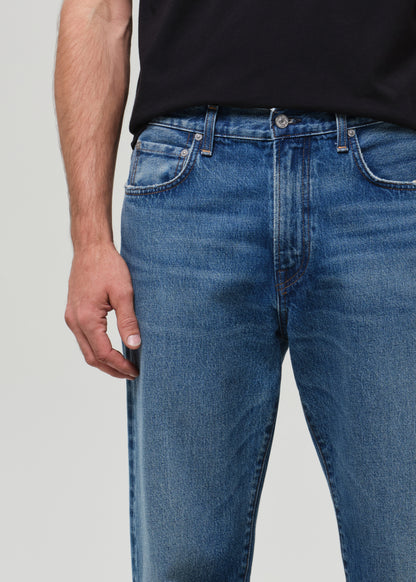 Person wearing blue jeans with a plain background