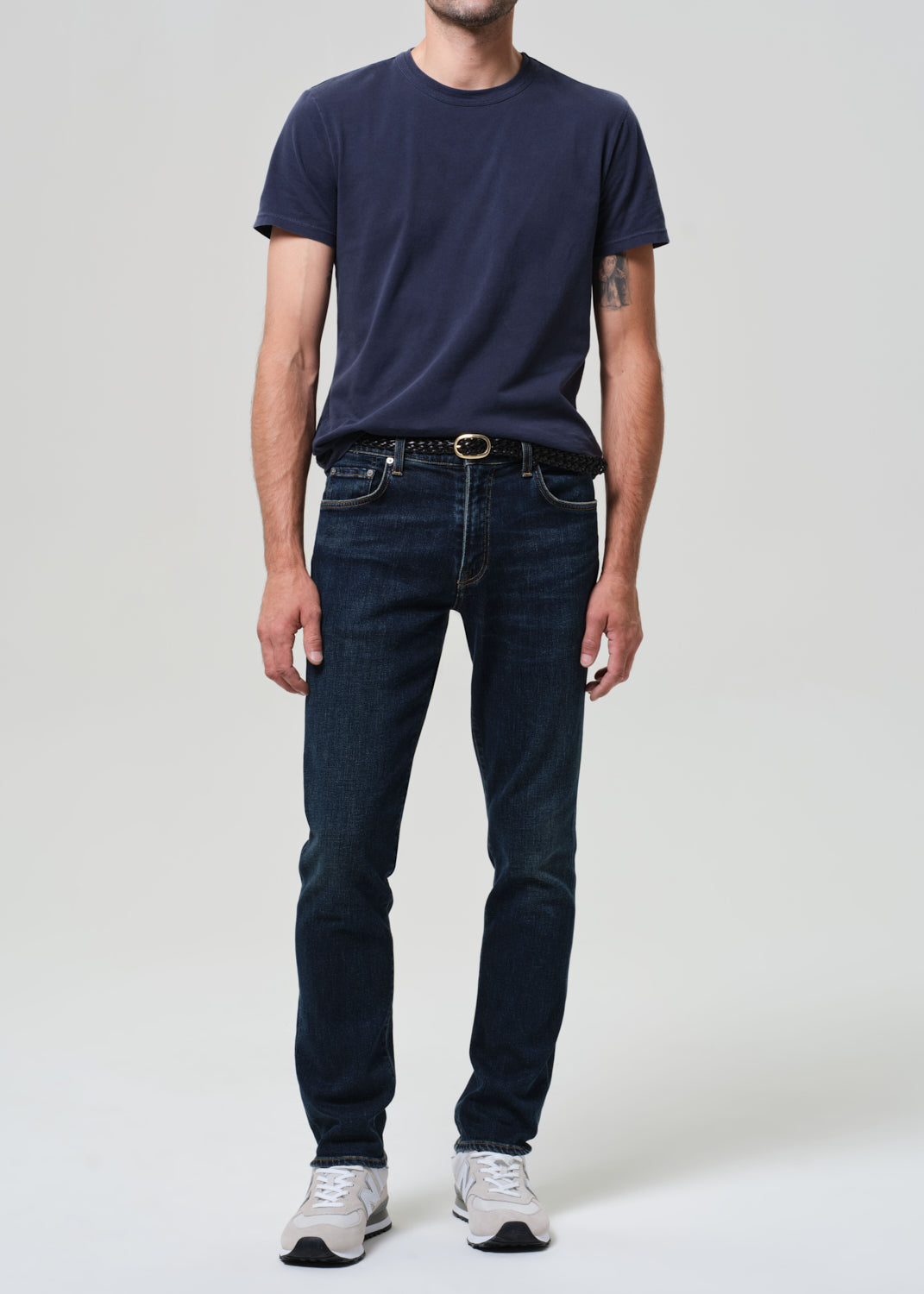 Person wearing a navy t-shirt and dark jeans on a plain background