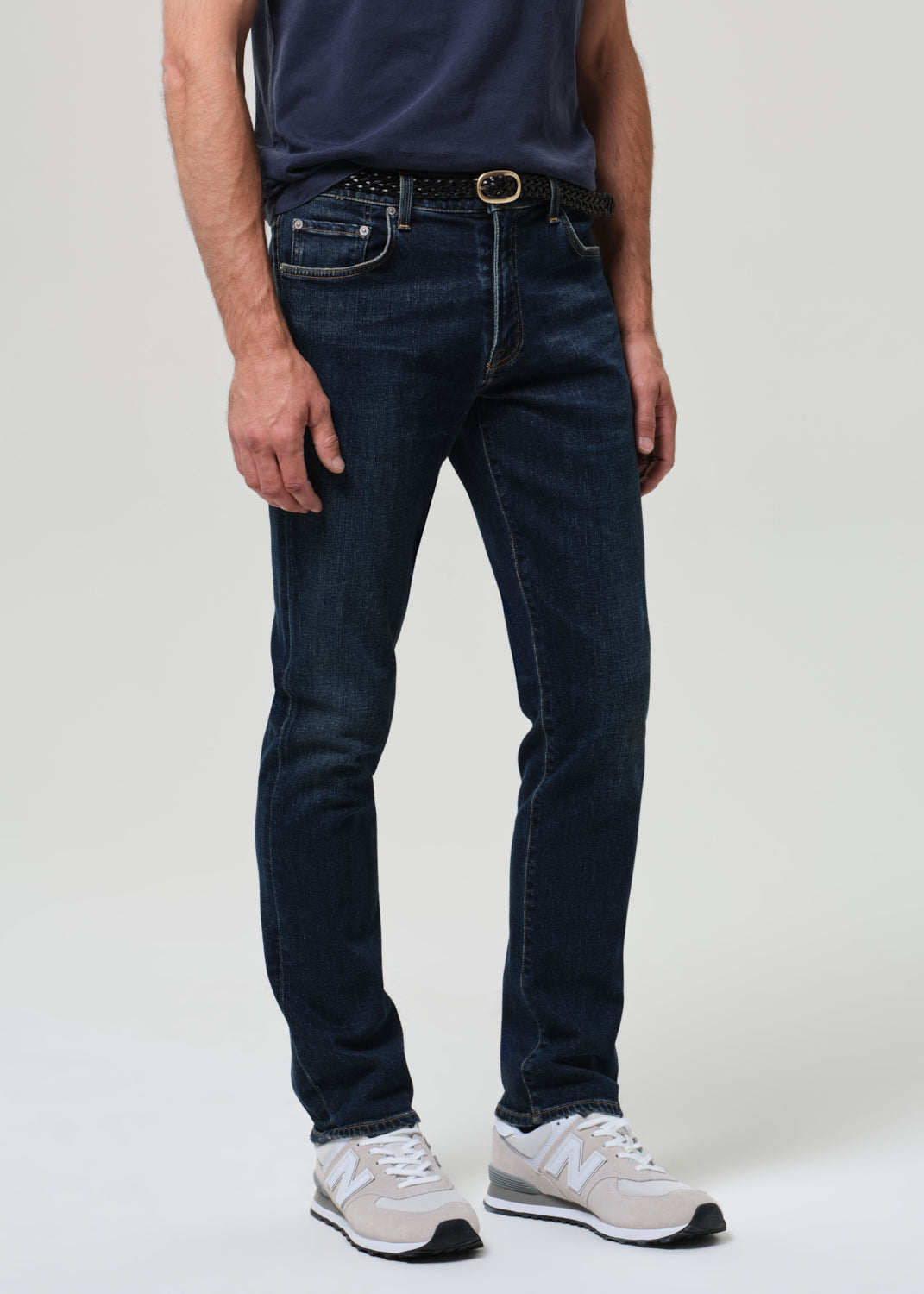 Person wearing a navy t-shirt and dark jeans on a plain background