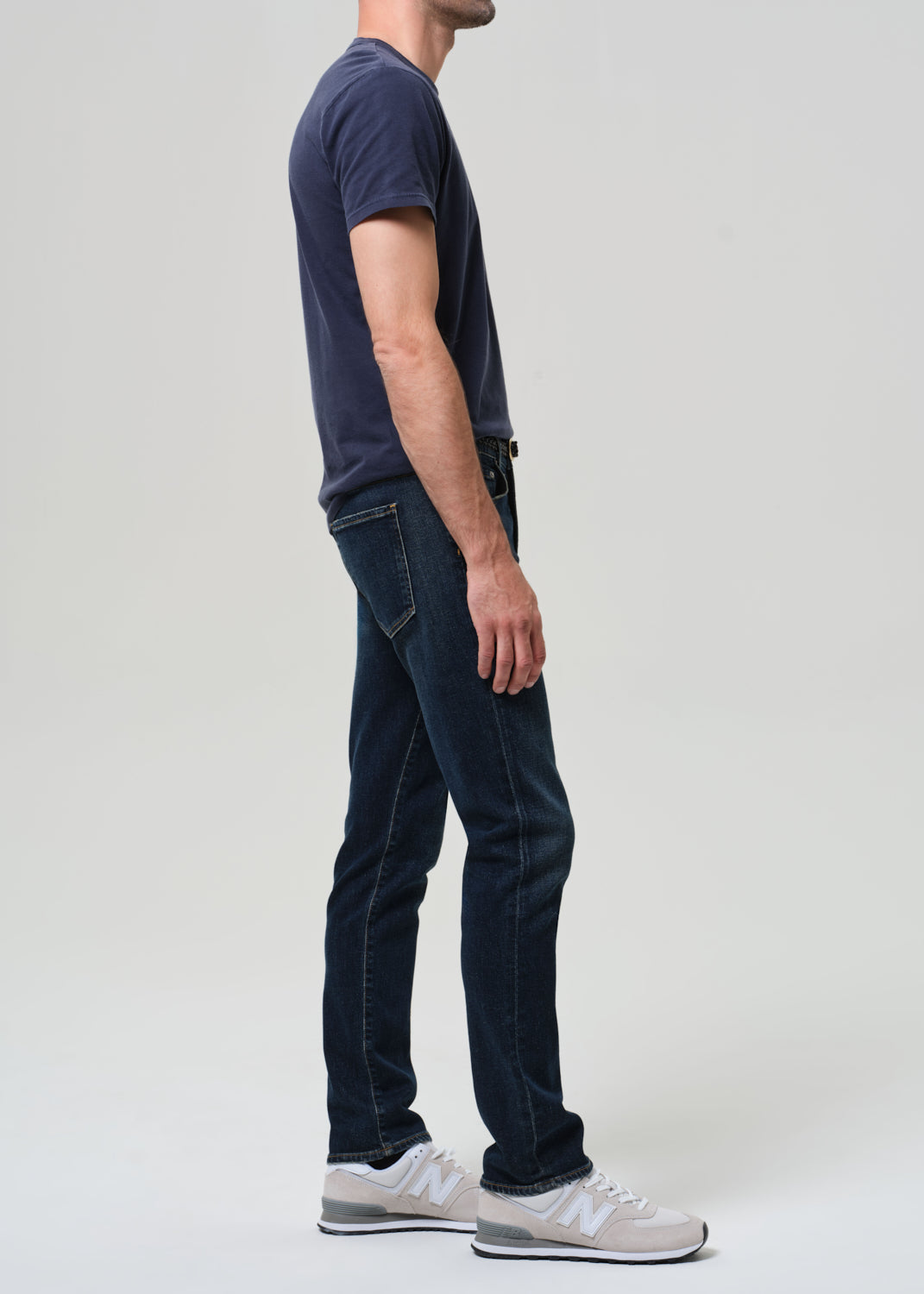 Person wearing a navy t-shirt and dark jeans on a plain background