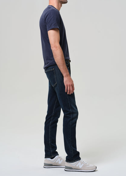 Person wearing a navy t-shirt and dark jeans on a plain background