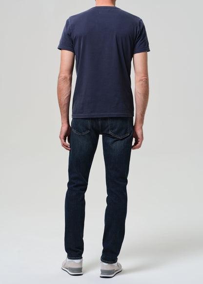 Person wearing a navy t-shirt and dark jeans on a plain background