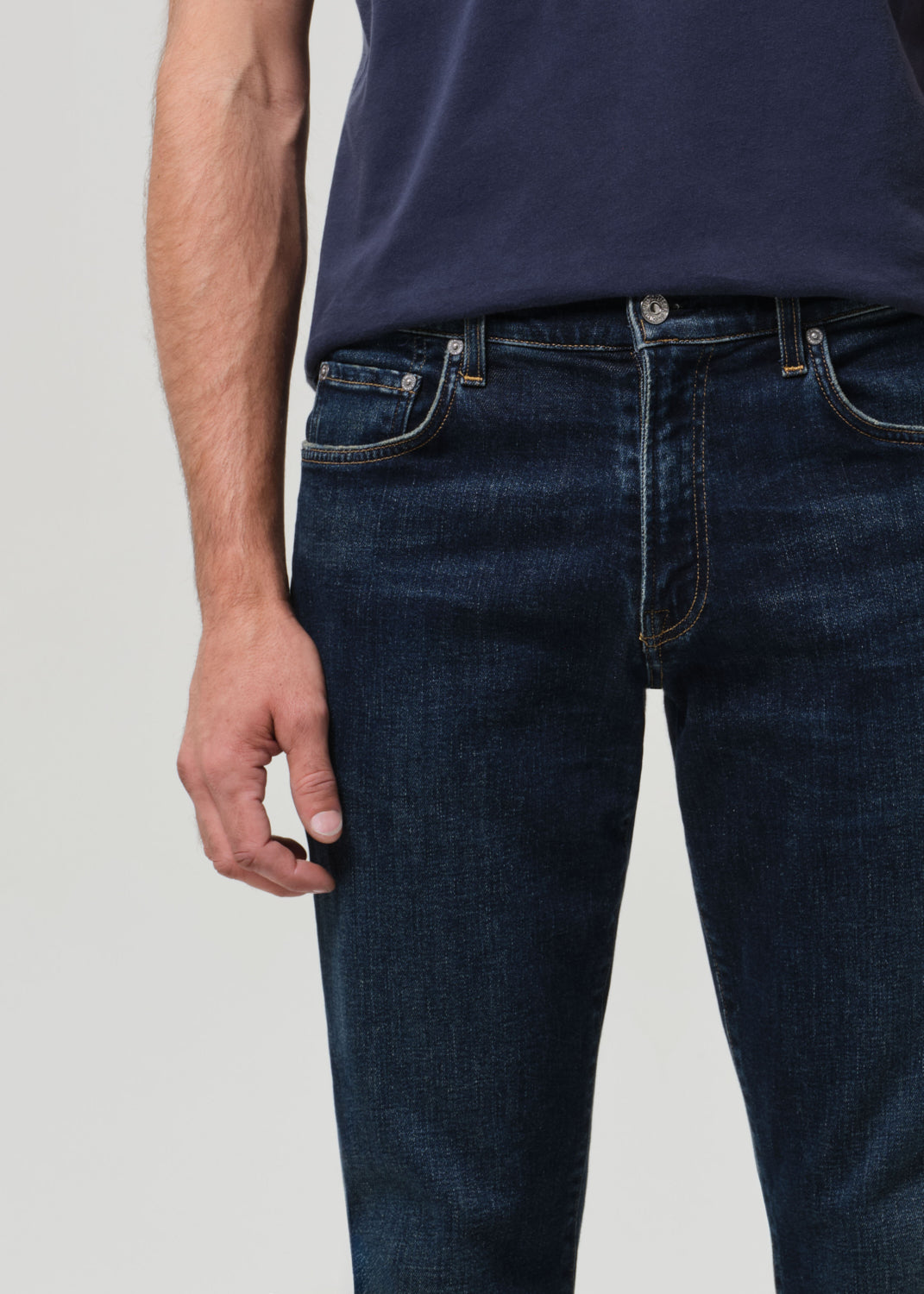 Person wearing a navy t-shirt and dark jeans on a plain background