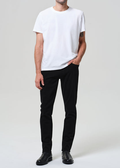 Person wearing a white t-shirt and black jeans on a plain background