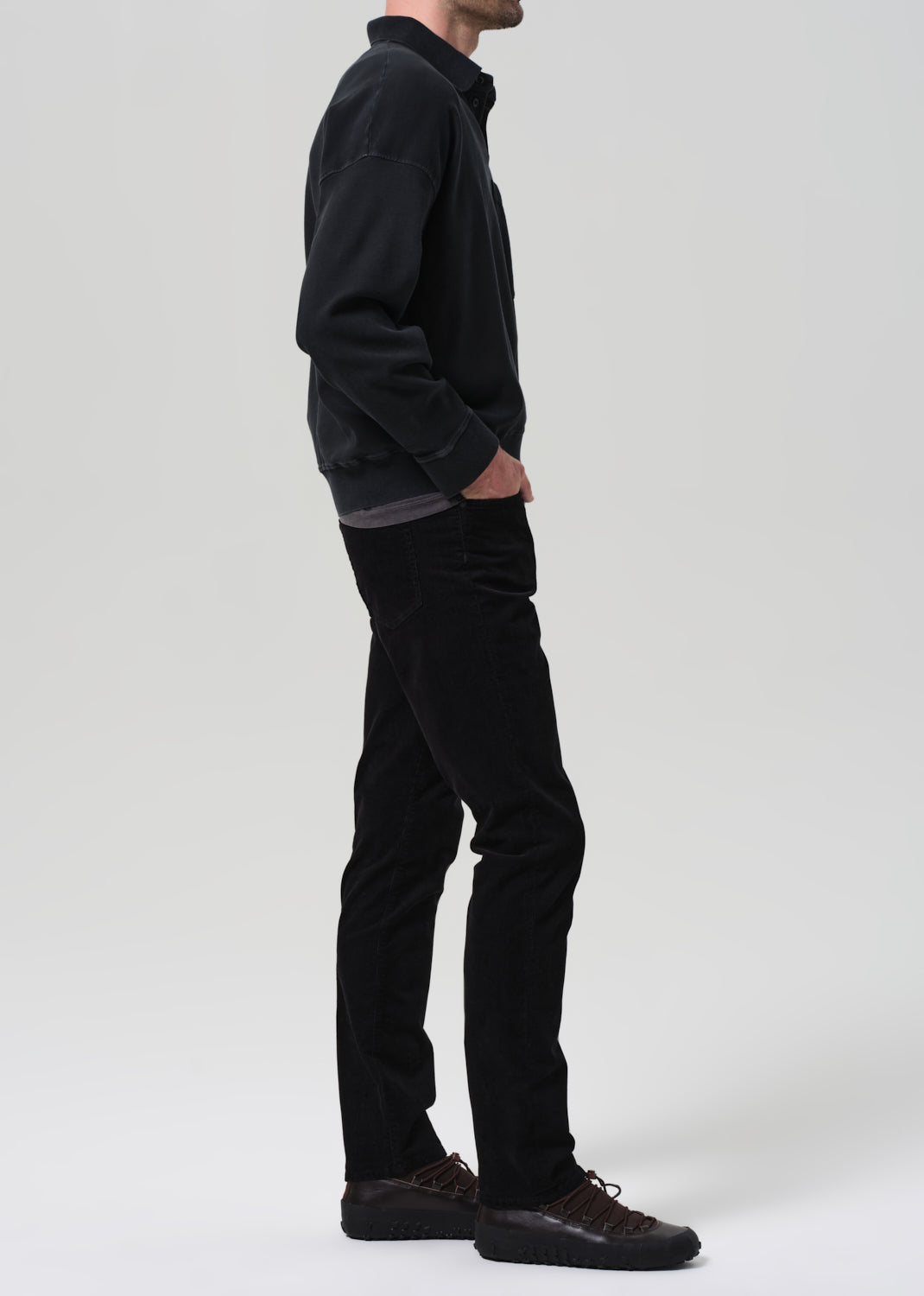 Person wearing black jacket and pants on a plain background
