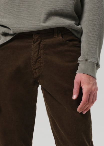 Person wearing a green sweater and brown pants on a plain background