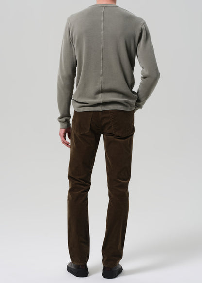 Person wearing a green sweater and brown pants on a plain background