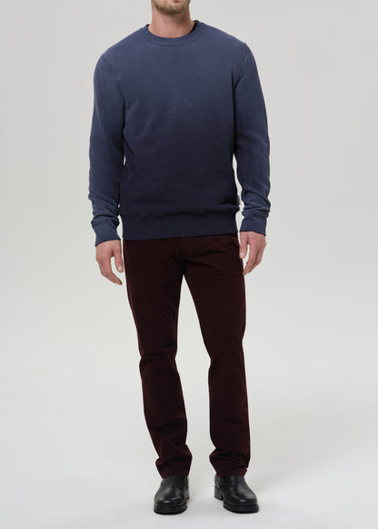 Person wearing a navy sweatshirt and burgundy pants on a light gray background
