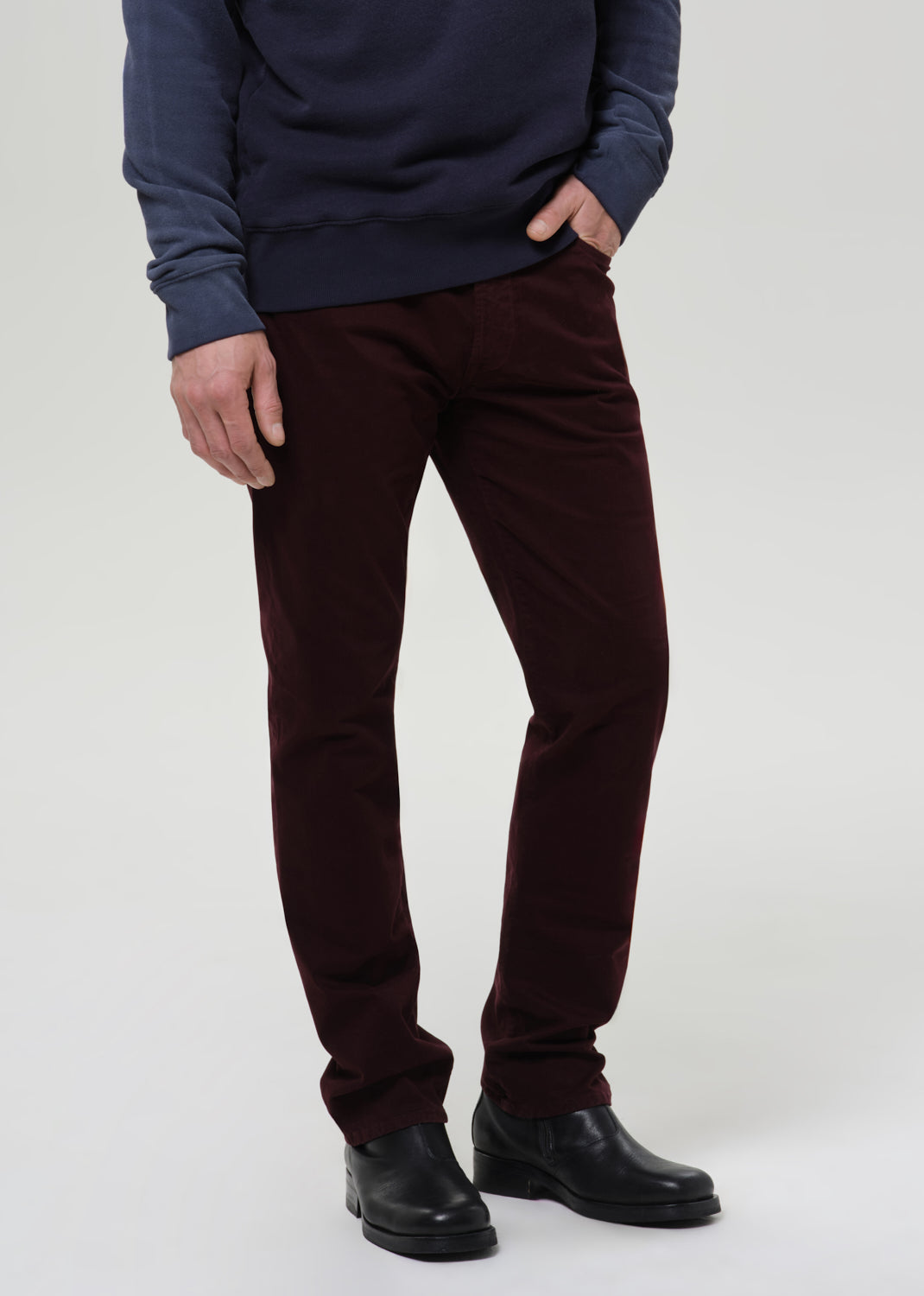 Person wearing a navy sweatshirt and burgundy pants on a light gray background