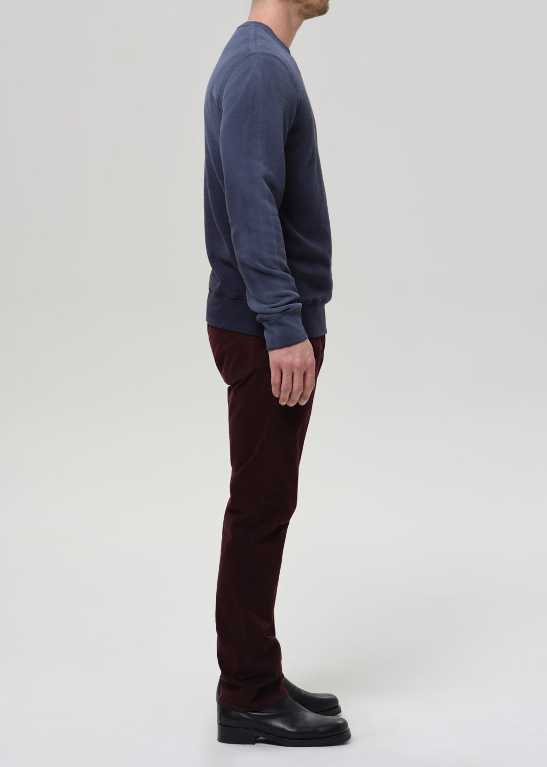 Person wearing a navy sweatshirt and burgundy pants on a light gray background