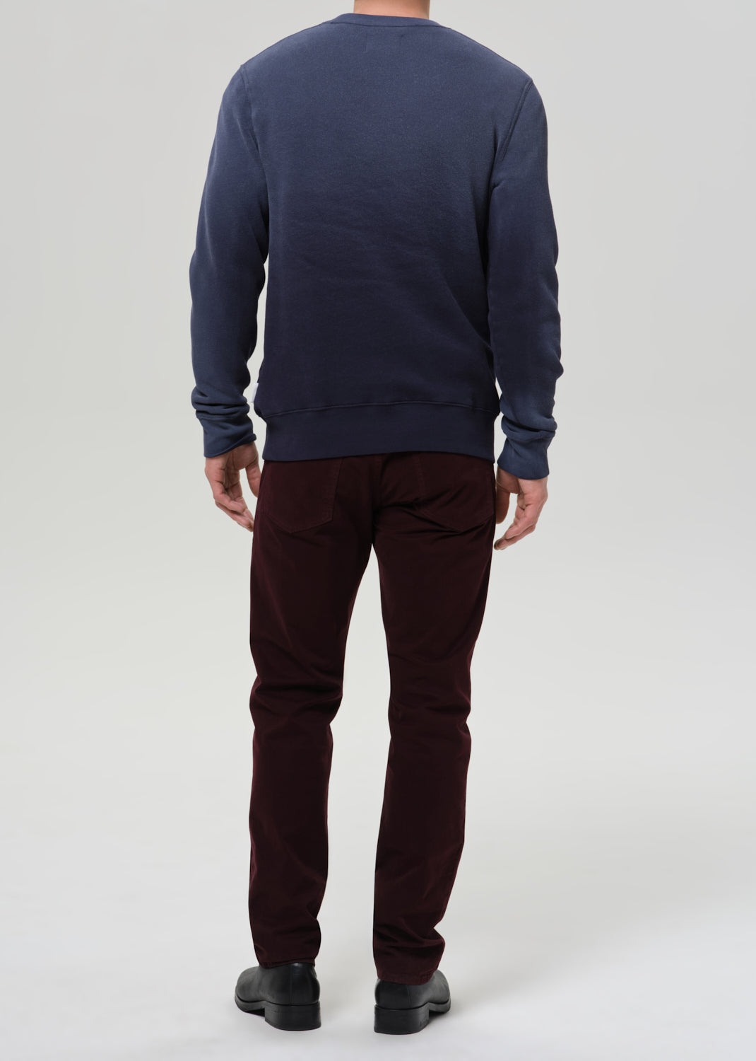 Person wearing a navy sweatshirt and burgundy pants on a light gray background