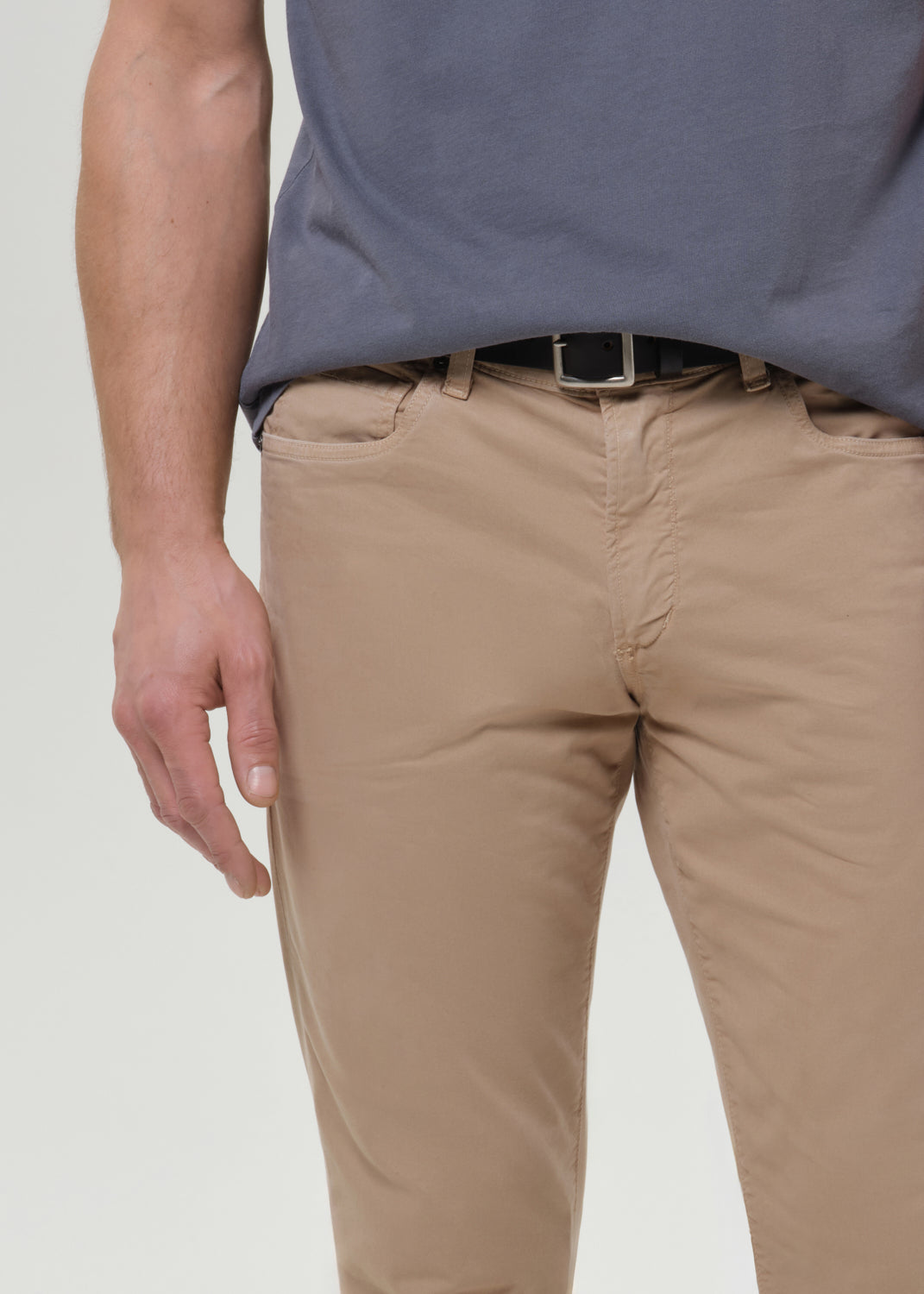 Man wearing a gray t-shirt and beige pants on a grey background