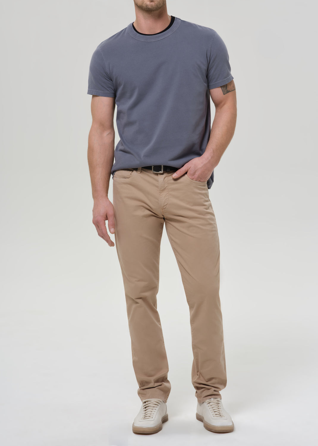 Man wearing a gray t-shirt and beige pants on a grey background