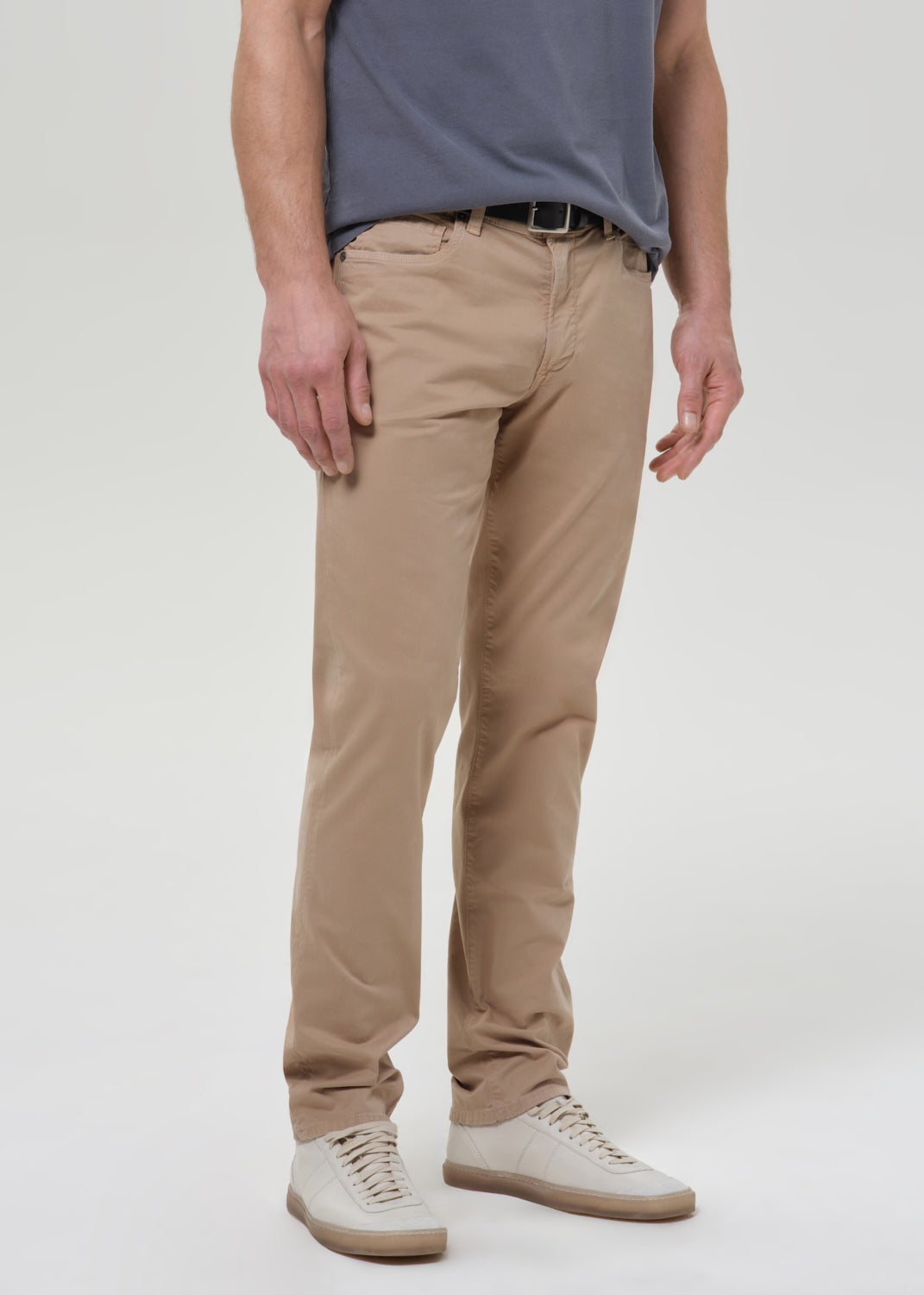Man wearing a gray t-shirt and beige pants on a grey background