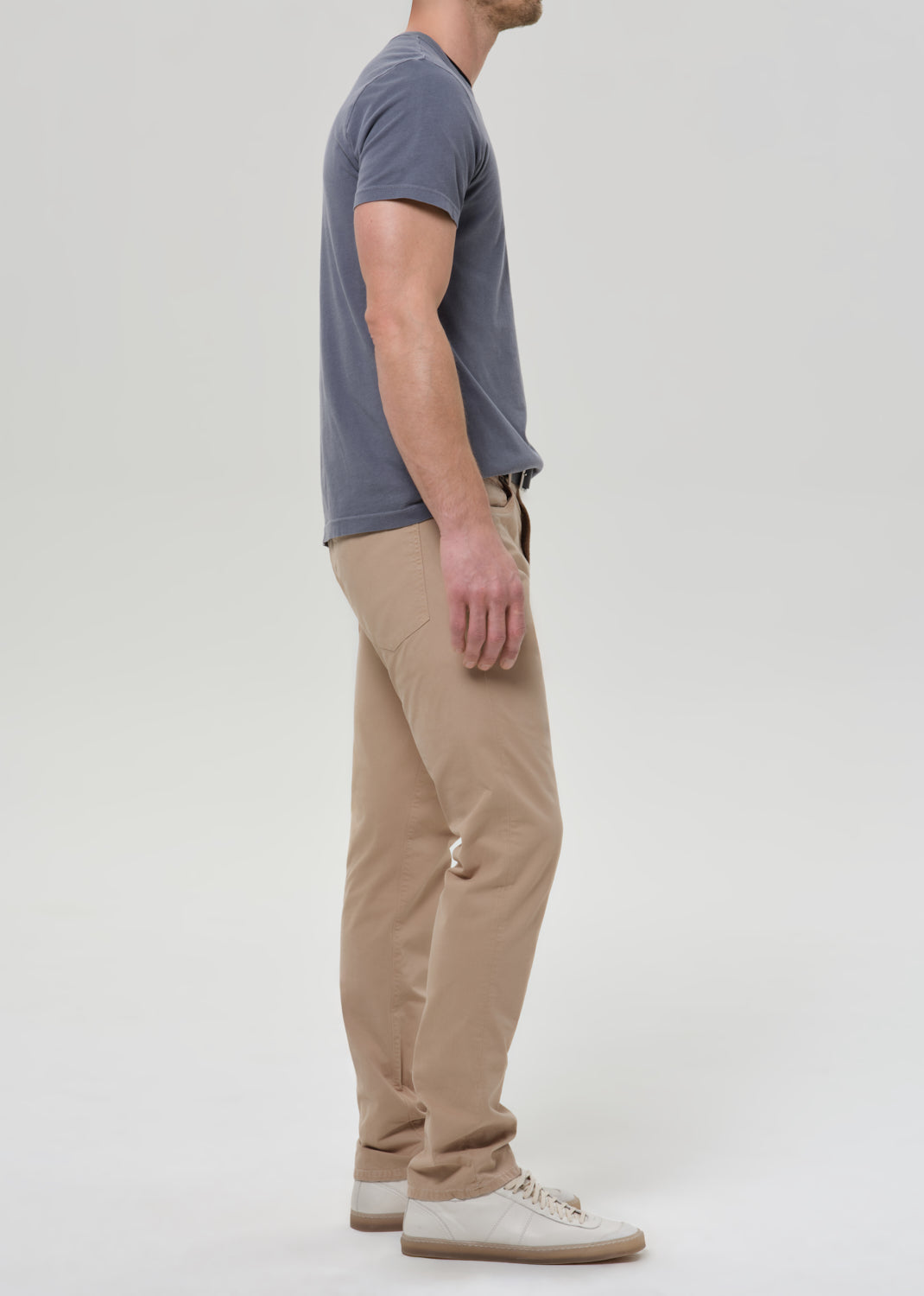 Man wearing a gray t-shirt and beige pants on a grey background