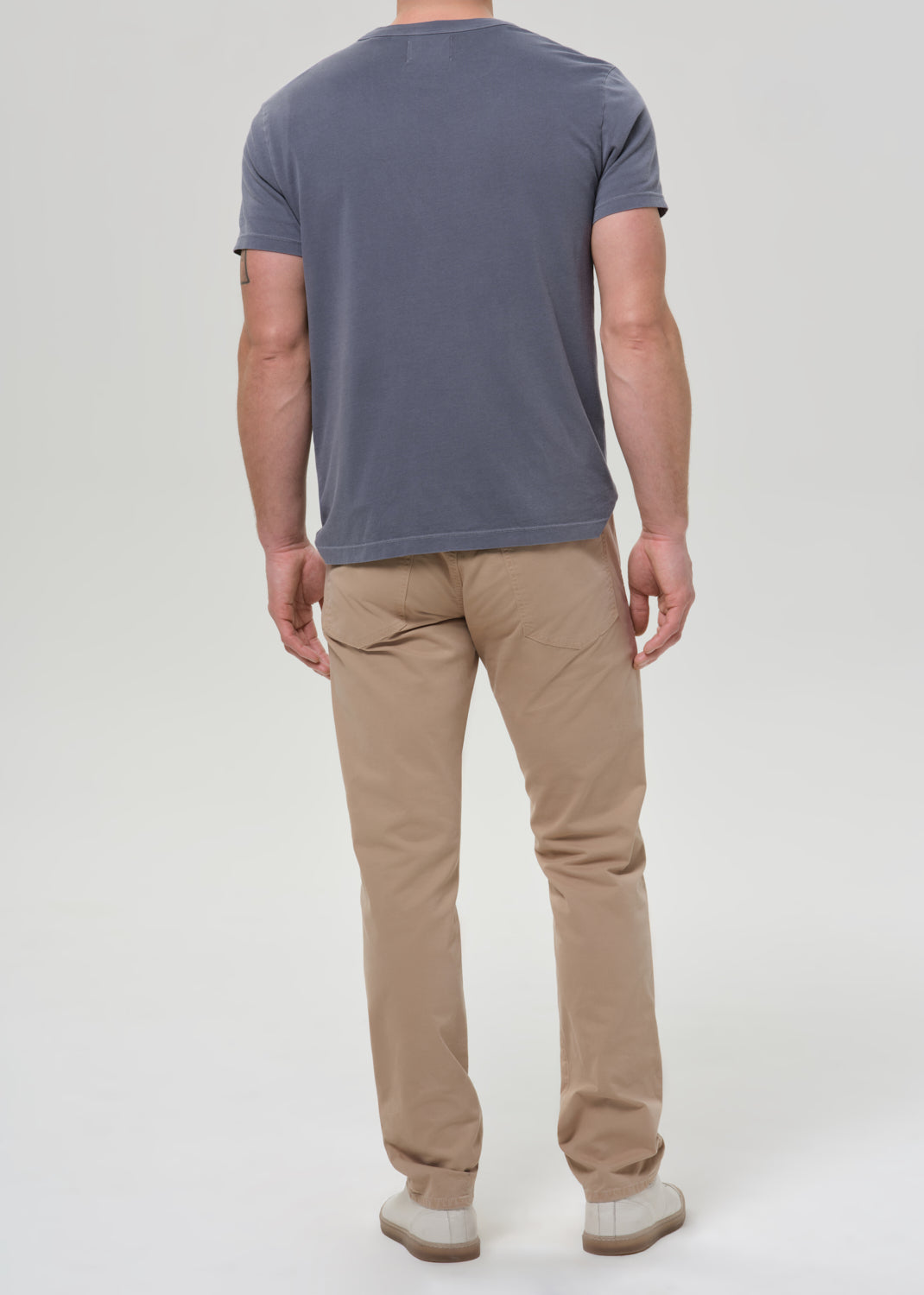 Man wearing a gray t-shirt and beige pants on a grey background