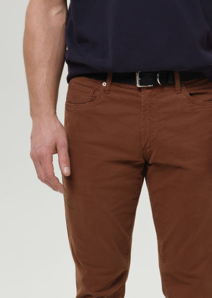 Close-up of brown straight leg pants on a grey background.