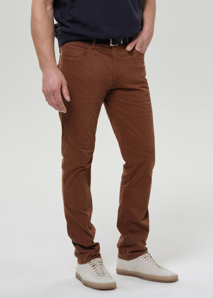 Person wearing brown straight leg pants with a navy crewneck short sleeve tee on a grey background.