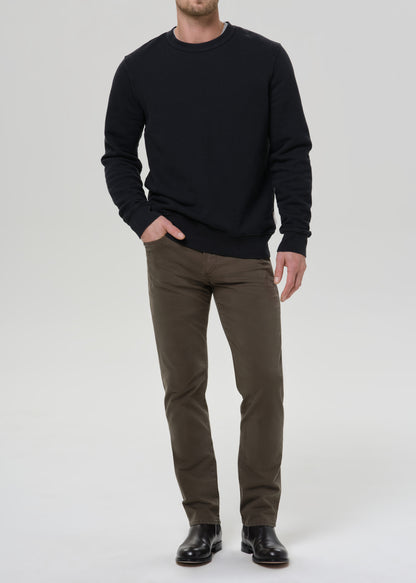 Man wearing a black sweatshirt and olive pants on a grey background