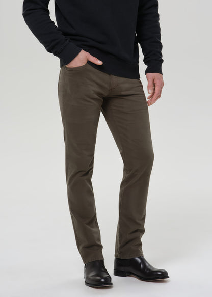 Man wearing a black sweatshirt and olive pants on a grey background