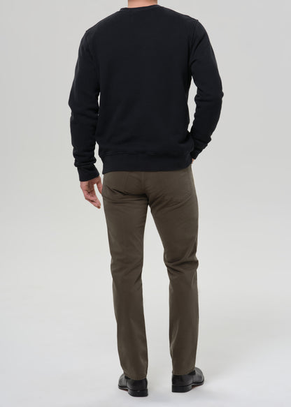 Man wearing a black sweatshirt and olive pants on a grey background