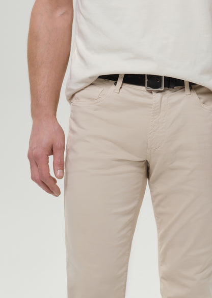 Close-up of cream straight leg pants on a grey background.