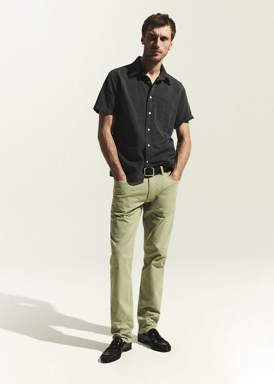 Man wearing a grey shirt and light green pants on a white background