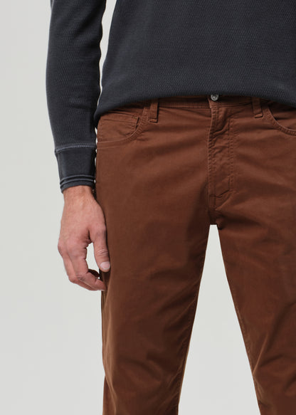 Person wearing a grey long-sleeve shirt and brown pants on a grey background