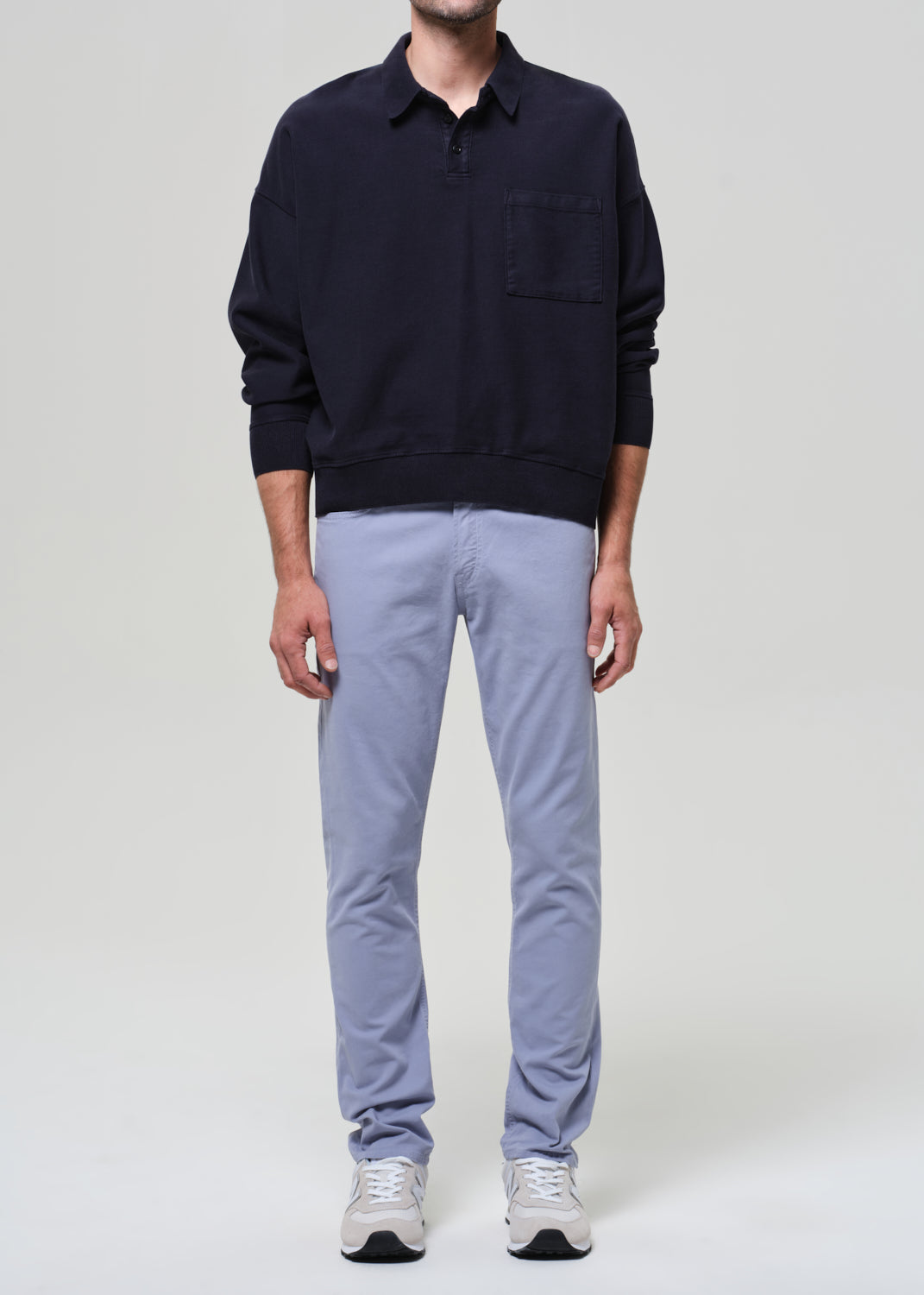 Person wearing a navy polo and light blue pants on a plain background