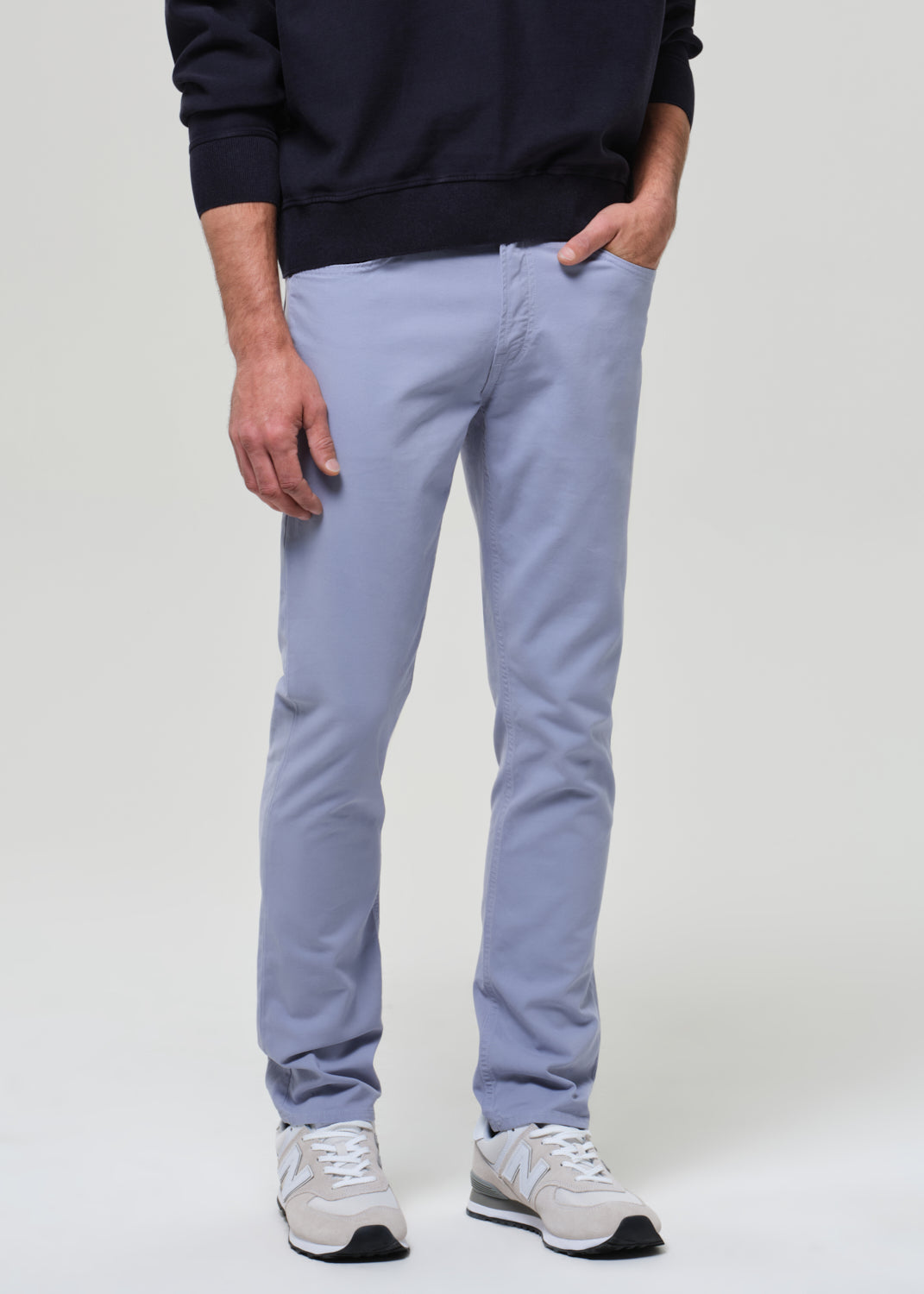 Person wearing a navy polo and light blue pants on a plain background