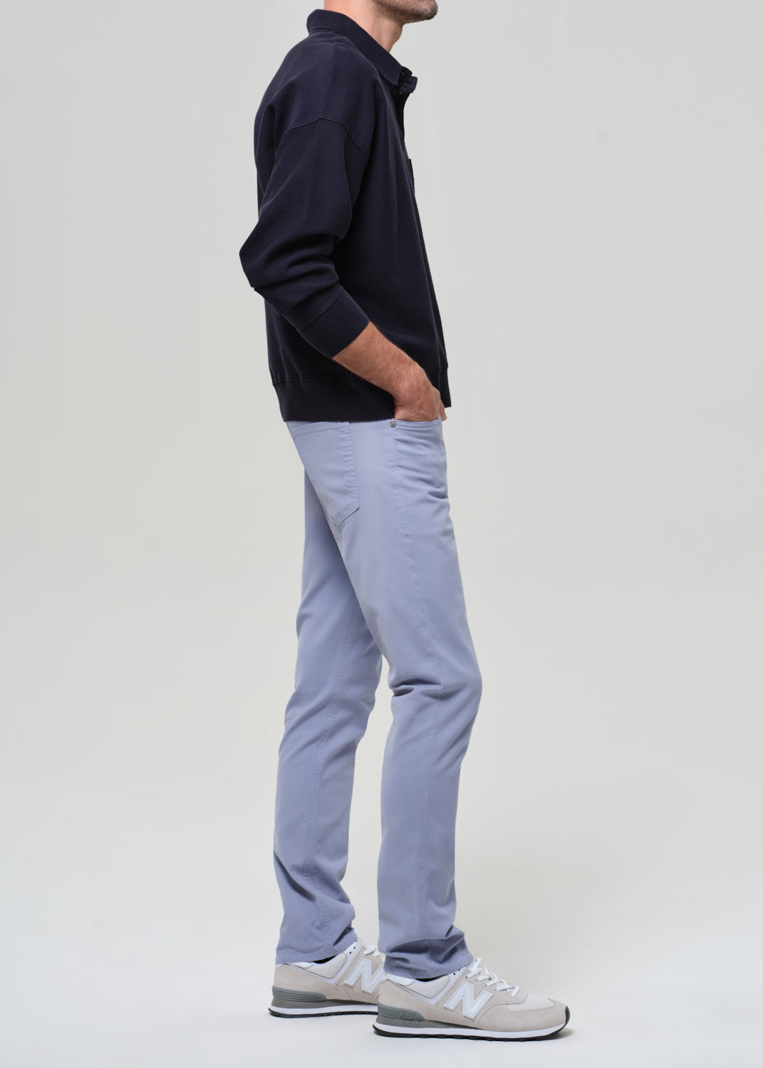 Person wearing a navy polo and light blue pants on a plain background