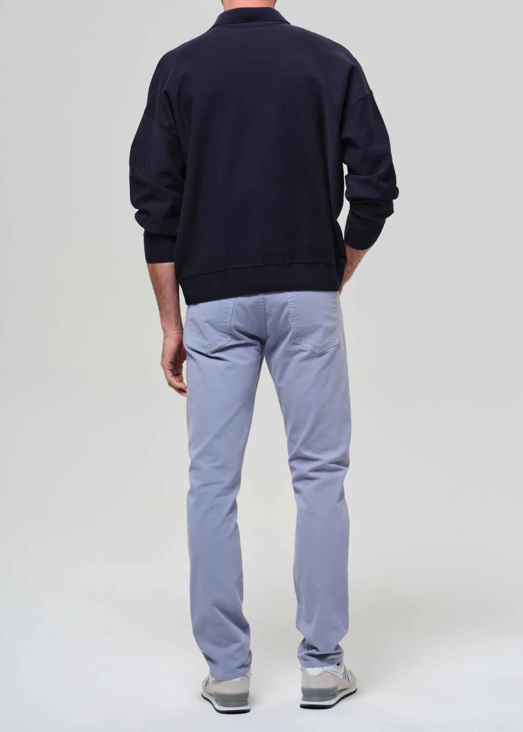 Person wearing a navy polo and light blue pants on a plain background